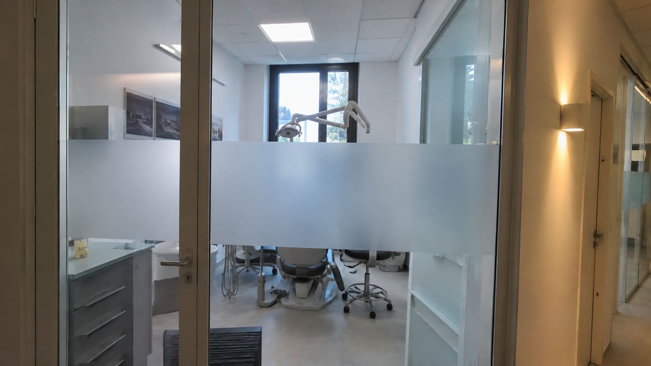 Glazen deur en wand met een brede matte band voor een behandelruimte.